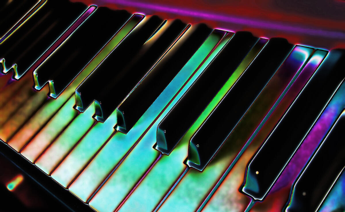 A multicoloured piano keyboard with red and purple console at the top. The white keys are recoloured to appear blue, green, and light red as though they are under coloured lighting. The black keys are unchanged in colour but have a glowing white outline.